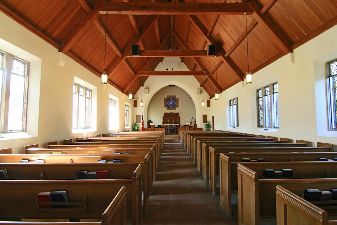 Interior de uma igreja com bancos de madeira e janelas altas